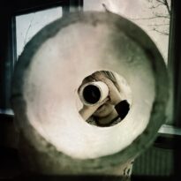 Barn tittar genom en tub i ett stort rörformat föremål inomhus.