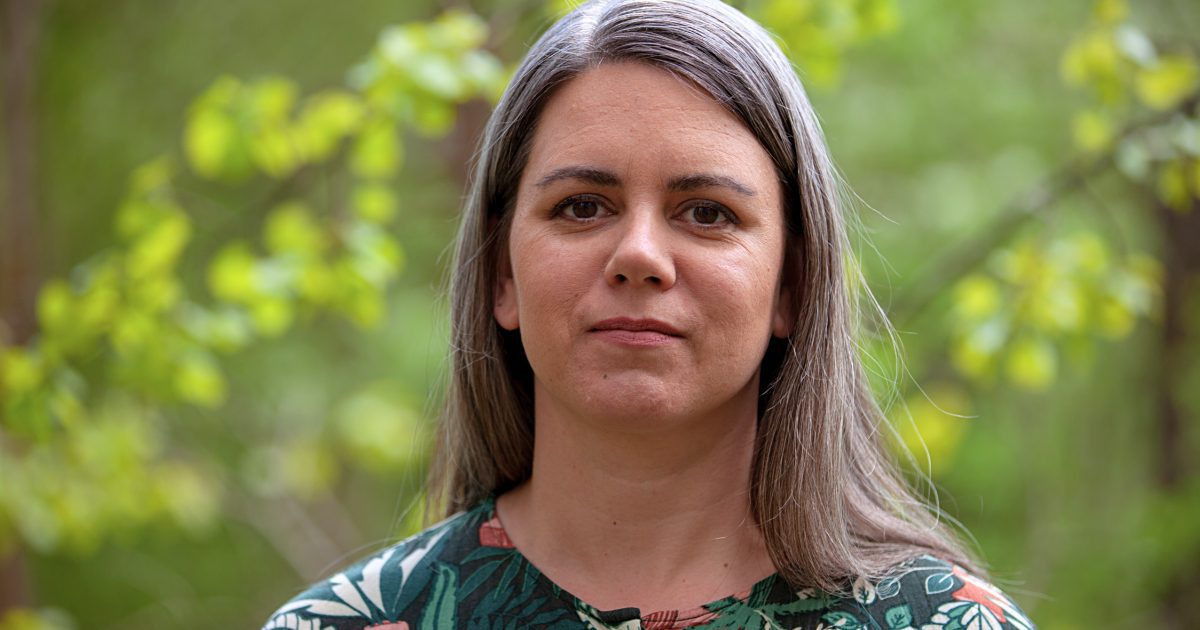 Porträtt på Signe Tonér utomhus mot grönskande bakgrund av träd.
