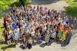 Gruppbild ovanifrån på 127 pedagoger utomhus en solig och grönskande dag.